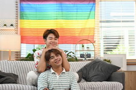Romantic young gay couple resting together on the sofa at home. LGBTQ people lifestyle concept.の写真素材