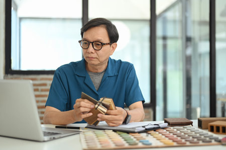 Experienced senior interior designer choosing material samples, working at creative office.の写真素材