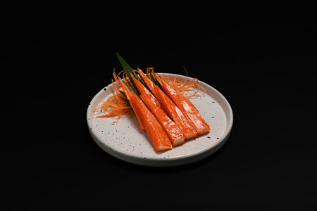 Crab sticks or surimi in white ceramic plate isolate on black background. Japanese food concept.の写真素材