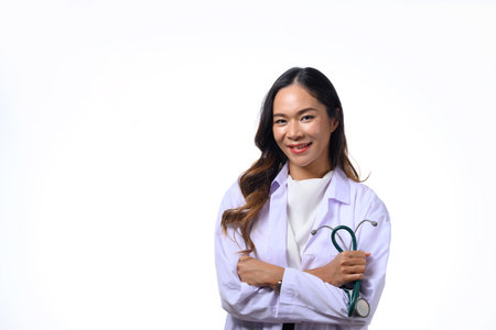 Portrait of female doctor holding stethoscope standing with arms folded isolated on white background.の写真素材