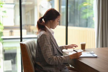 Side view of financial accountant sitting at desk working reviewing financial data or accounting statistics.の写真素材