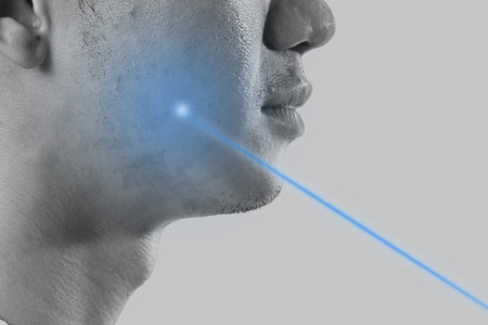 Closeup man with blue bright laser beam directed at the skin for rejuvenation. Aesthetic face treatment concept.の写真素材