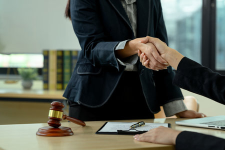 Cropped shot of lawyer shaking hands with clients in the office after a successful agreement, closing a deal.の写真素材