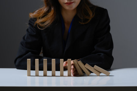 Businessperson hand stopping falling wooden blocks. Financial risk management, prevention and development to stability.の写真素材