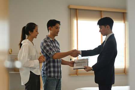 Realtor shaking hands with young couple with their purchase. Real estate and property purchase...