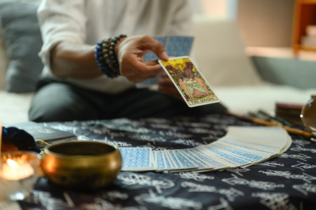 Fortune teller hand revealing The Lovers tarot card during a reading session.Concept of witchcraft and divination.の写真素材