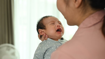 Loving asian mother comforting baby son in her arms. Childcare and motherhood concept.