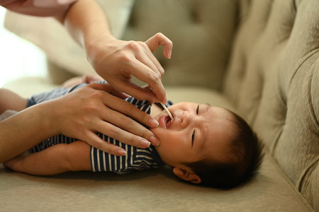 Mother using medical long cotton swab gauze to cleaning baby tongue. Child care and motherhood concept.の写真素材