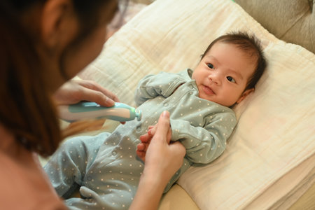 Mother cutting fingernails of her newborn baby and using baby nail trimmer. Child care and...