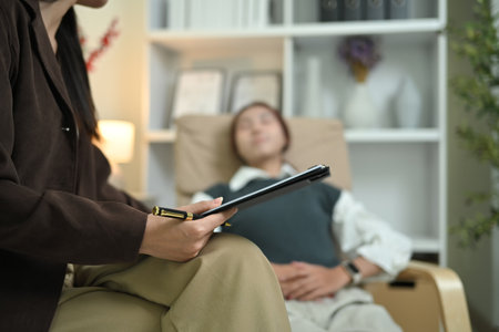 Close up female psychologist taking detailed notes while talking with patient during therapy session.の写真素材