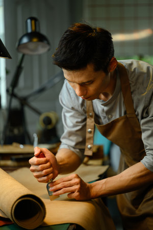 Concentrated of leather craftsman tailor cutting brown leather patterns in atelier workshop. Handmade concept.の写真素材