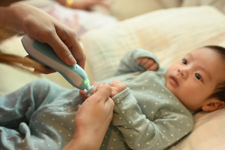 Cropped shot mother cutting fingernails of her newborn baby and using baby nail trimmer. Child care...