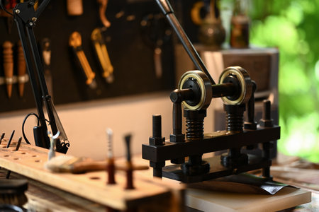 An iron press machine on wooden table in leather workshop.