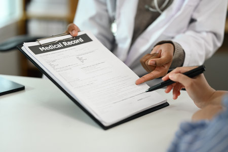Close up of female patient signing medical document at doctor office. Healthcare coverage policy.の写真素材