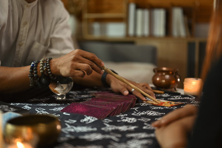 Cropped shot of soothsayer doing Tarot card reading and forecasting future for client in dark room.の写真素材