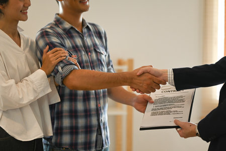Young couple shaking hands with realtor. Real estate and property purchase concept