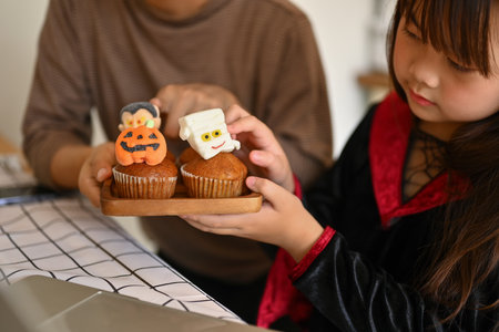 Cropped shot of little girl decorating Halloween cupcakes with different monsters.の写真素材
