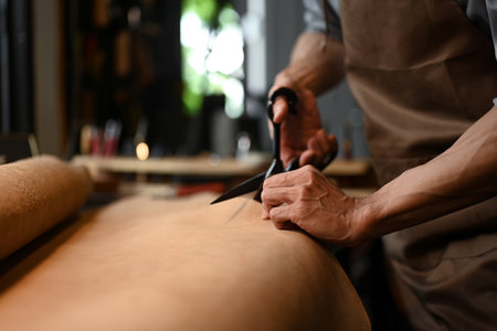 A craftsman working diligently, cutting leather in his workshop with various tools
