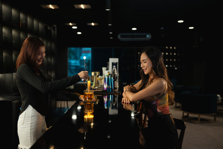 Pretty asian female bartender stirring whisky in glass at bar counter. Drinks and party concept.の写真素材