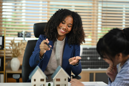 Smiling African American female realtor negotiating with client. New house and real estate concept.の写真素材