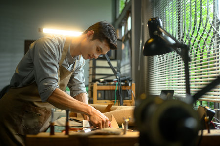 Dedicated craftsman focusing intently on his task at workshop.の写真素材