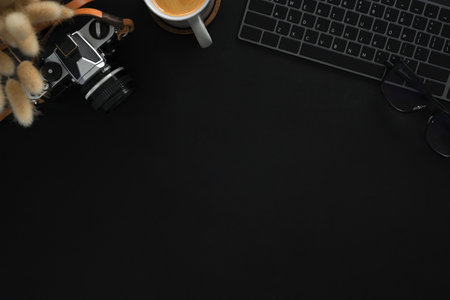 A vintage camera, keyboard and a cup of coffee on black background. Flat lay, Top view with copy space.の写真素材