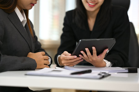 Two young businesswomen collaborating on their new project at modern office.の写真素材