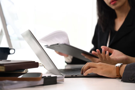 Two young colleagues discussing project and reviewing papers together at office.の写真素材