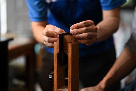 Close up shot of artisan hands meticulously stitches pieces of leather.の写真素材