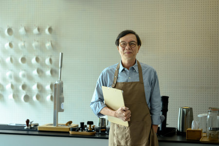 Portrait of middle aged cafe owner holding menu standing in front of the counter.