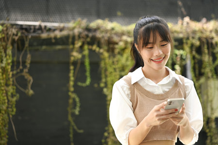 Beautiful young asian woman using smartphone outdoors. Lifestyle, technology and communication concept.の写真素材