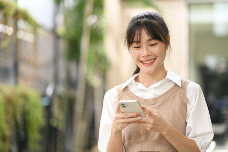 Beautiful young asian woman using smartphone outdoors. Lifestyle, technology and communication concept.の写真素材