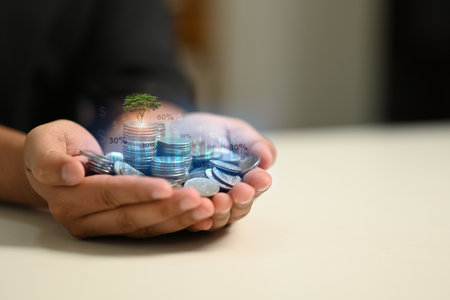 Hands holding a pile of coins with a tree. Investment, business growth and finance sustainable concept.の写真素材