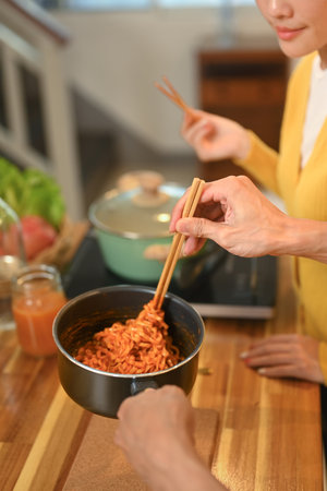 Young couple eating freshly cooked instant noodles on the wooden countertop.の写真素材