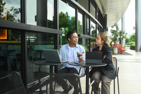 Young businesspeople having discussion at an outdoor cafe. Business discussions, teamwork and remote...