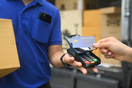 Delivery man delivering a package to a customer and receiving payment with credit card.の写真素材