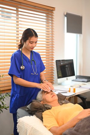 Elderly woman having Reiki healing treatment with therapist in clinic. Alternative medicine concept.の写真素材