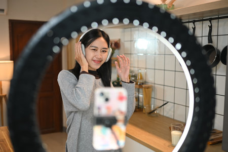 Pretty female influencer having fun dancing while recording video, creating content for social...