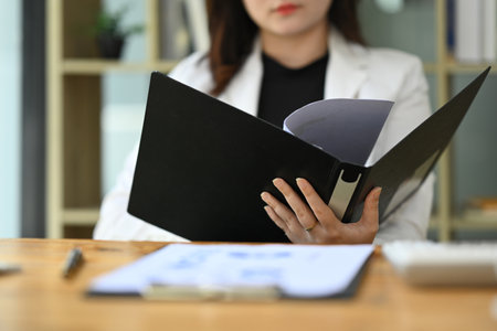 Cropped shot of professional businesswoman reviewing financial document at desk.の写真素材