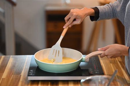 Cropped shot of young woman making simple scrambled egg for breakfast.の写真素材