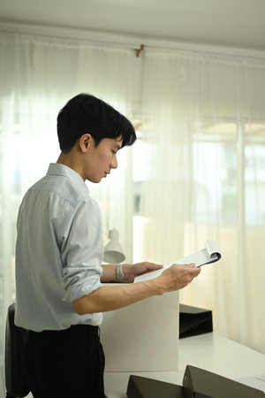 Handsome male account manager checking reports at his office desk.
