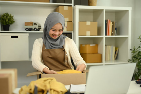 Young muslim woman packing parcel boxes of product for shipping to customers. E-commerce and Online selling concept.の写真素材