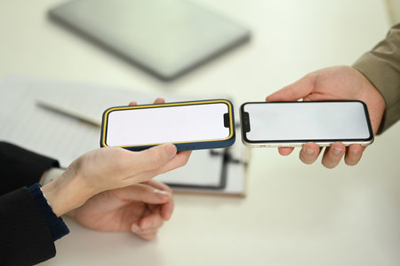 Young men sharing data or contact through their smartphone. Technology, data transfer, or...