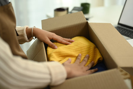 Small business owner packing products in boxes for delivery to customer. E-commerce concept.