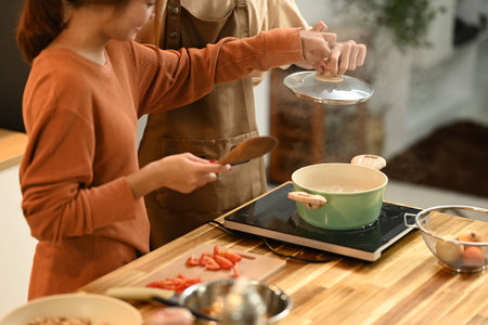 Young couple preparing a delicious meal together in the kitchen. People, food and lifestyle concept.