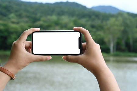 Hands holding a smartphone taking a picture of beautiful landscape.の写真素材