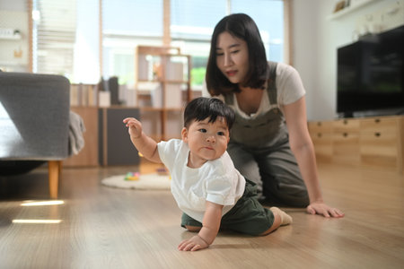 Curious baby boy crawling on floor with mother. Child development and parenting concept.