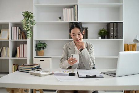 Successful young entrepreneur using smartphone at desk.の写真素材