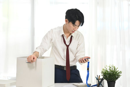 Frustrated man looking at his ID badge while preparing to leave his job.の写真素材