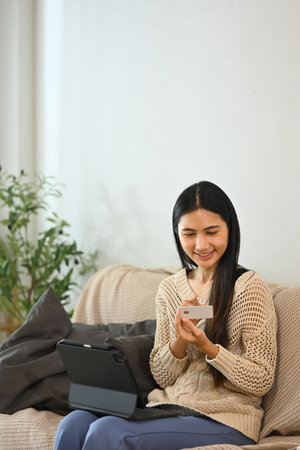 Happy female shopper using credit card for online shopping at home.の写真素材